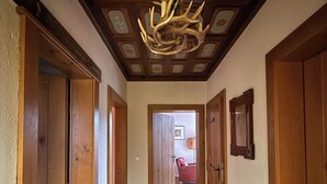 Ein Flur mit Holztüren, einer Chandelüster und einem gefliesten Boden.
