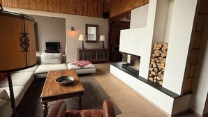 Ein gemütliches Wohnzimmer mit Kamin, einer Couch, einem Couchtisch und einem Fernseher.