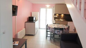 Un espacio habitable compacto con kitchenette, comedor y escalera.