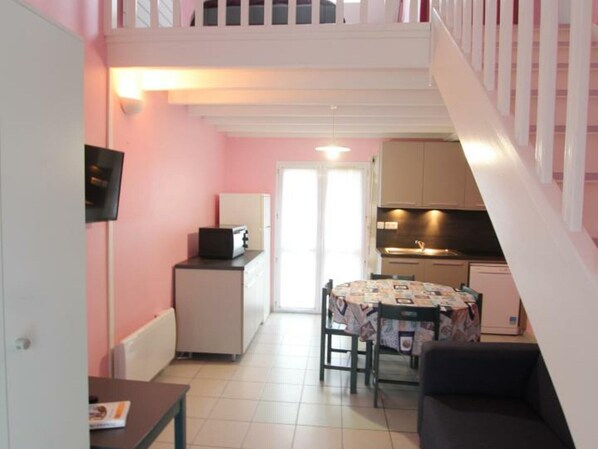 A compact living space with a kitchenette, a dining area, and a staircase.