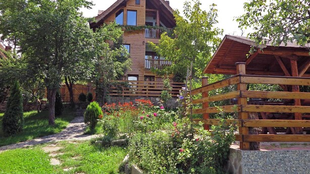 A wooden cabin with a balcony, surrounded by a garden with various plants and flowers. - • CASA ZOLLO II • cosy studio apartment in a quaint Carpathian village, Sibiu (Sibiu)