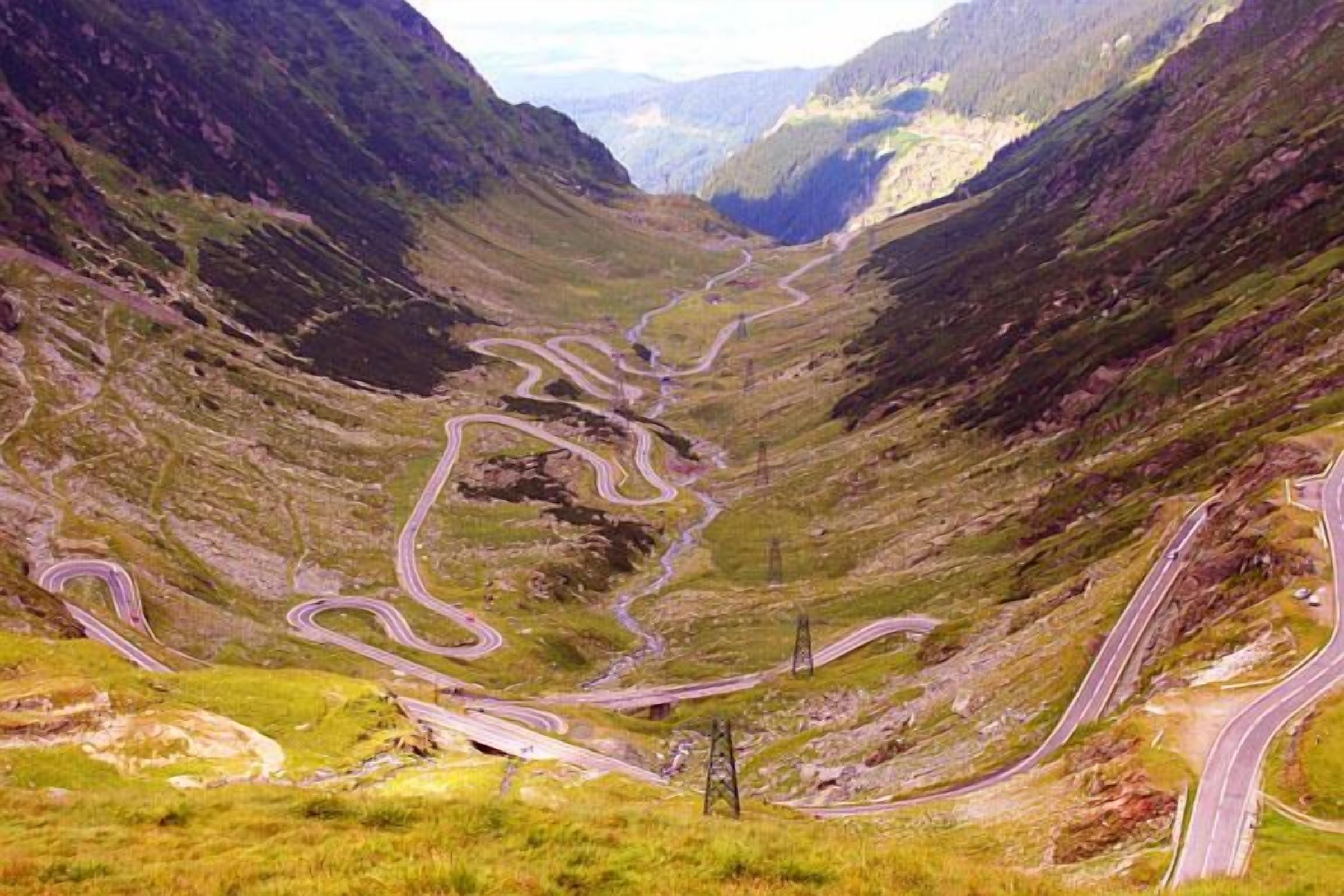 A winding mountain road with multiple lanes, surrounded by steep hills and sparse vegetation.
