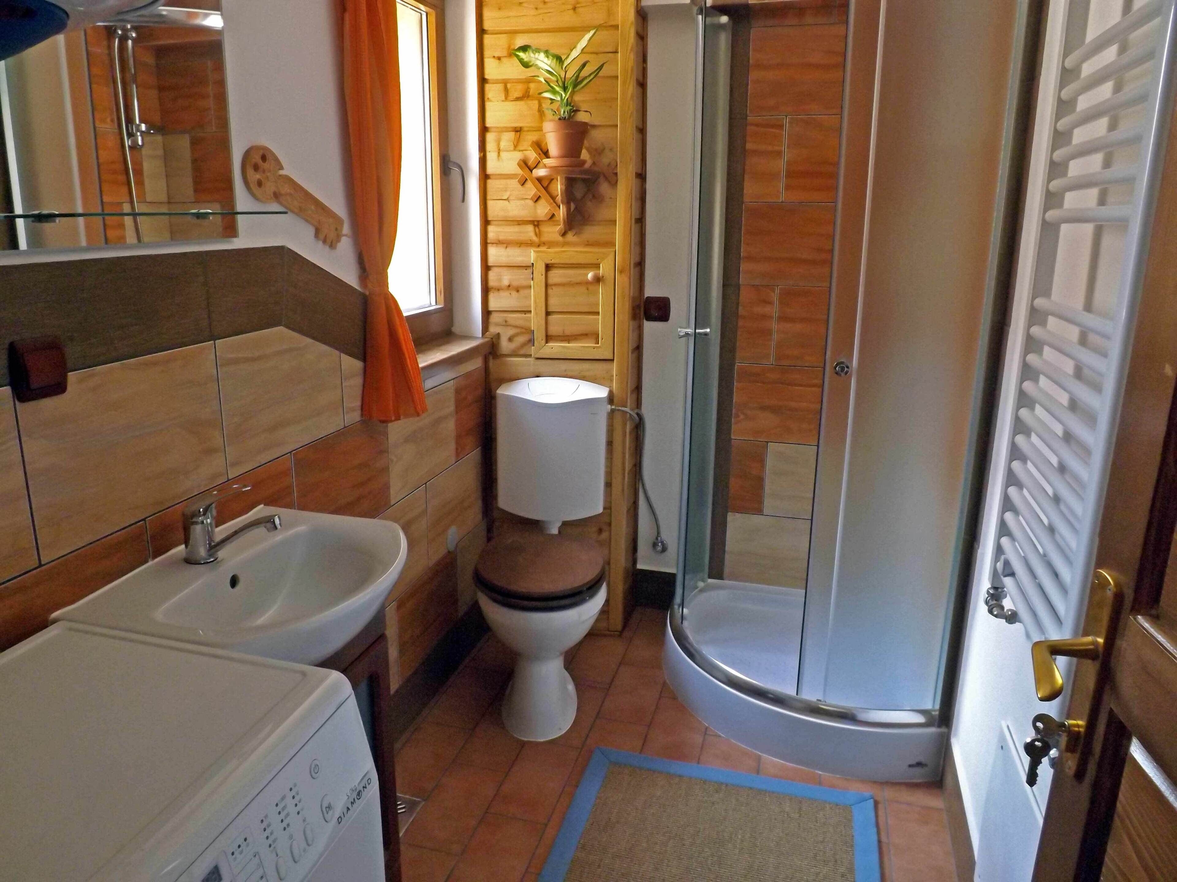 Ein Badezimmer mit Dusche, Toilette, Waschbecken und einer Waschmaschine.