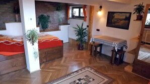 A cozy room with a bed, a table, and a chair. There are potted plants and a painting on the wall. - • CASA ZOLLO II • cosy studio apartment in a quaint Carpathian village, Sibiu (Sibiu)