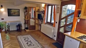 A compact kitchen with a refrigerator, a stove, and a dining area with a table and chairs. - • CASA ZOLLO II • cosy studio apartment in a quaint Carpathian village, Sibiu (Sibiu)