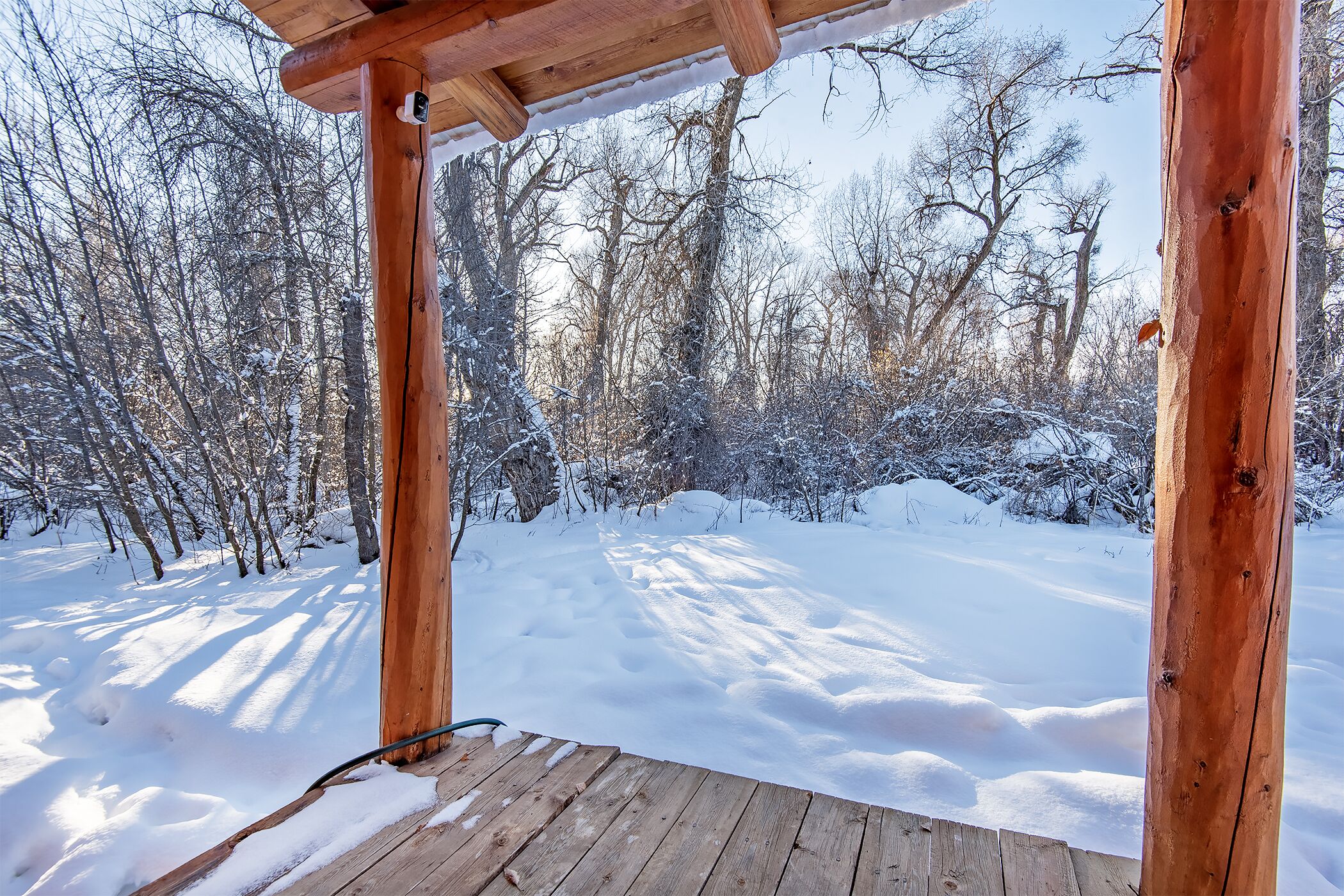Una terraza de madera con vista a un bosque cubierto de nieve.