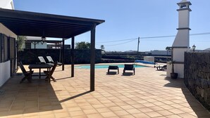 Un área de patio techada con sillones de descanso y una piscina.