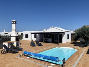 Une maison moderne dotée d’une piscine, d’un espace salon extérieur et d’une cheminée.