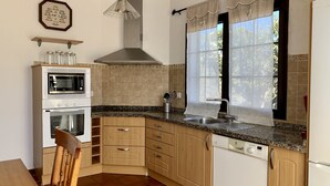 Una cocina con microondas, horno, fregadero y armarios de madera.