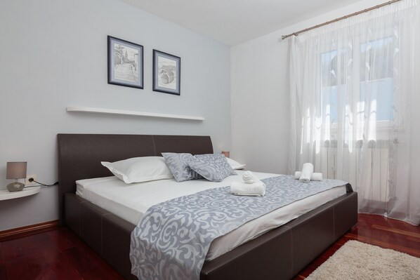 A modern bedroom with a large bed, a bedside table, and two framed pictures on the wall.