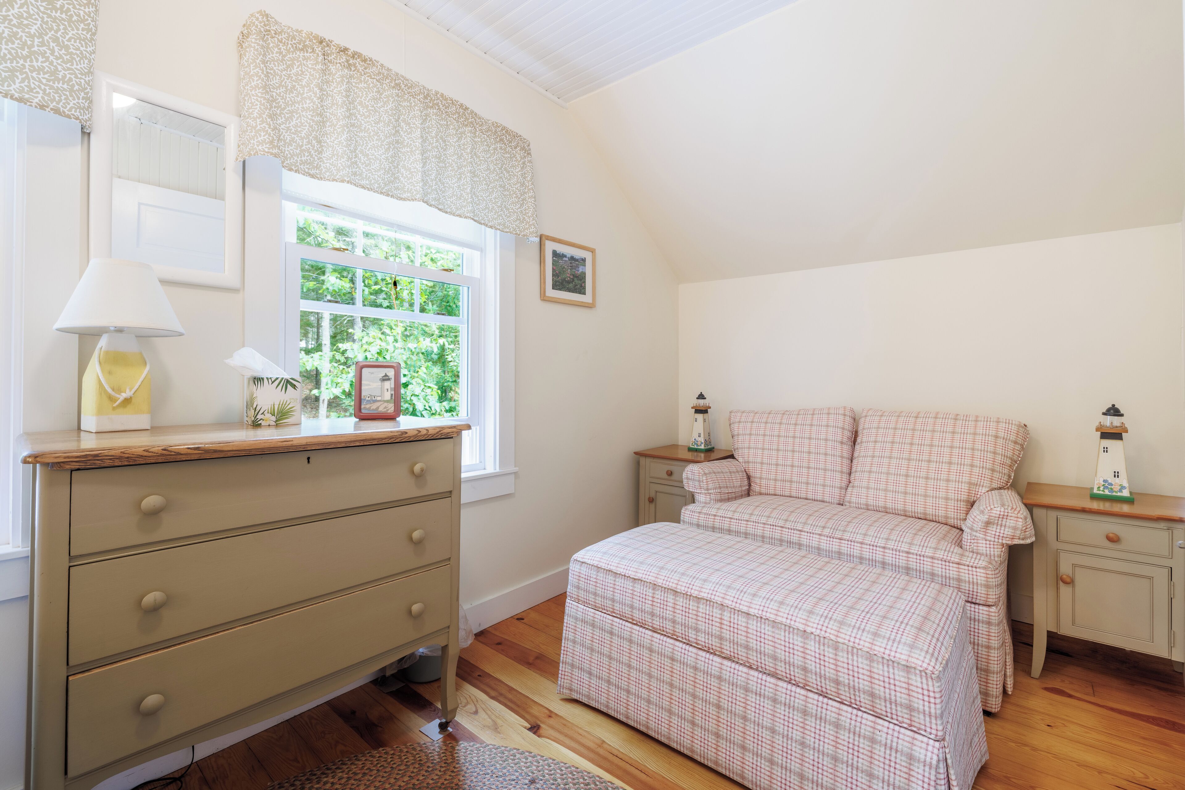 A bedroom with a bed, dresser, nightstands, a window with curtains, and a lamp.