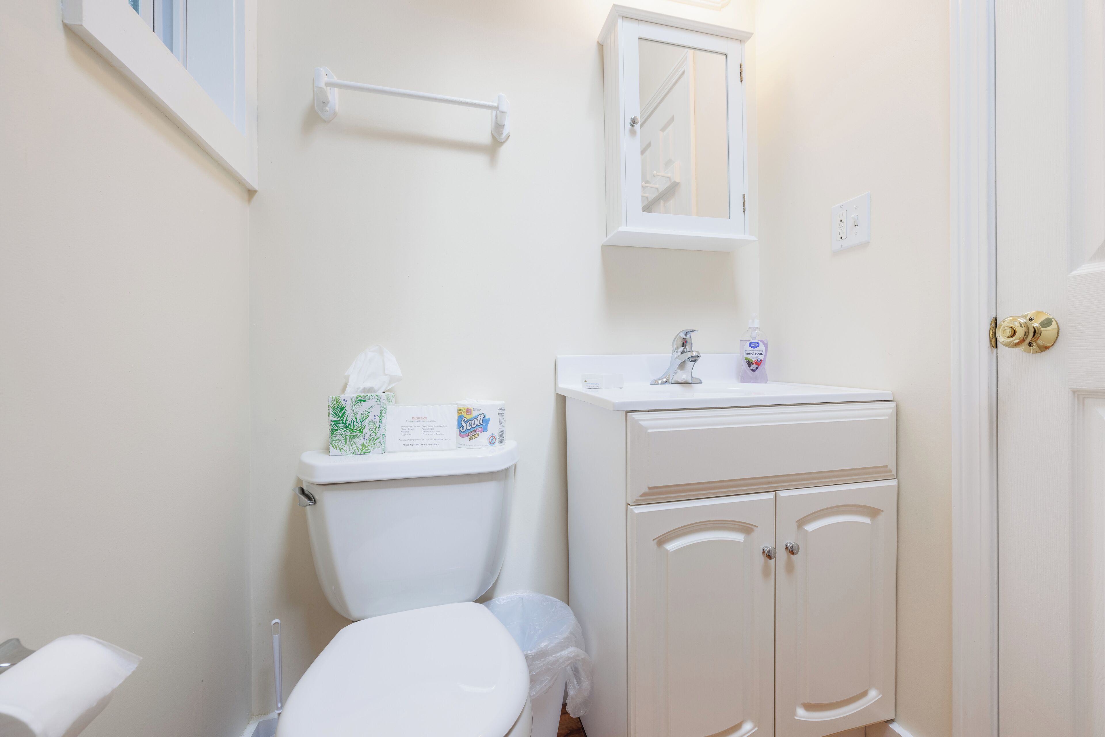 A bathroom with a toilet, sink, and cabinet.