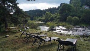 Eine Flusslage mit Außenbestuhlung und einer hölzernen Bank.