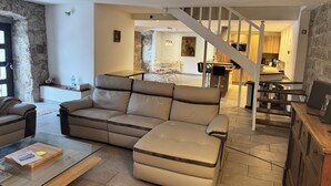 Ein modernes Wohnzimmer mit Sofa, Couchtisch und einer Treppe, die in einen Küchenbereich führt.