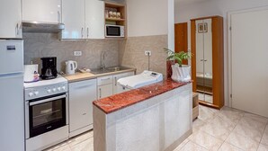 Una cocina moderna con armarios blancos, un microondas integrado, una cafetera y un lavabo.