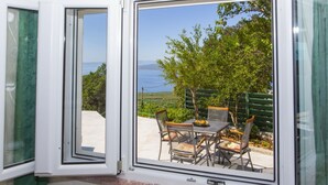 Ein Zimmer mit einem großen Fenster und Blick auf eine Terrasse mit Tisch und Stühlen.