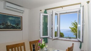 Ein Esszimmer mit einem Tisch für vier Personen, einem Bild an der Wand und einem Fenster mit Meerblick.