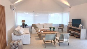 A modern living room with a sofa, chairs, a coffee table, and a TV.
