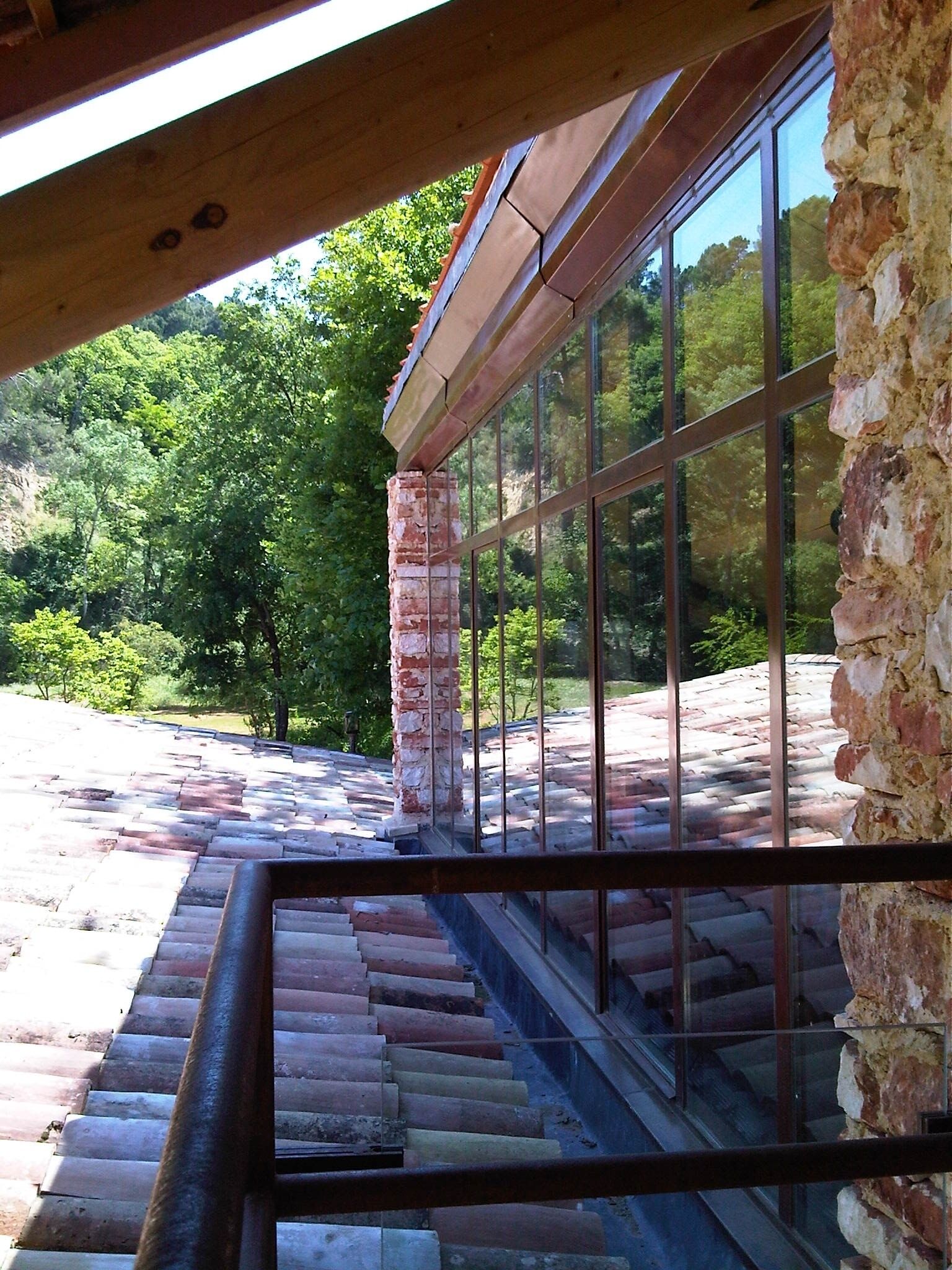 A staircase leading to a glass-enclosed area with a view of a forested hillside.