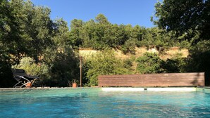 Una piscina de blau clar envoltada d'arbres i una tanca de fusta.