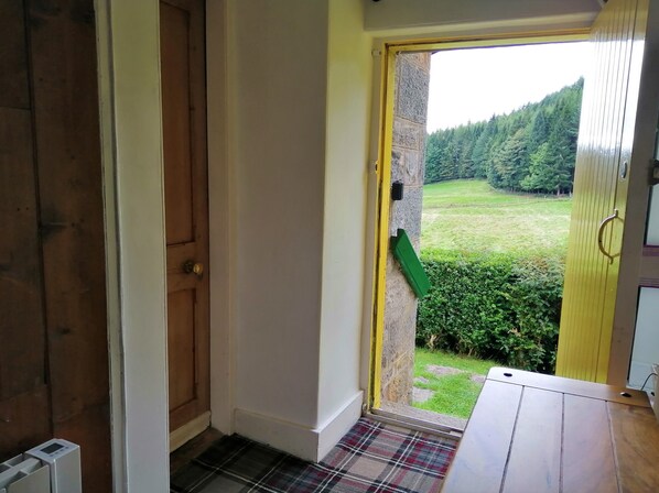 A hallway leading to a door with a view of a green landscape. - Traditional highland cottage with magnificent panoramic views (invernesshire)