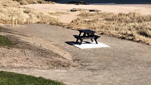 A beach with a concrete path leading to a picnic table. - Traditional highland cottage with magnificent panoramic views  (invernesshire)
