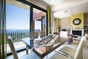 Relax in a spacious living area with a balcony offering a scenic view, featuring a dining table, fireplace, and bookshelf.