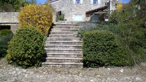 A stone house with a steep staircase leading to a door with a white frame. - The Country House Mijotiere (monestier)