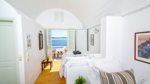 Une chambre à coucher avec un lit, une plante en pot et une vue sur la mer.
