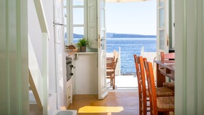 Une cuisine avec vue sur la mer, des chaises en bois et une table.