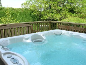 Ein Whirlpool mit einer Holzterrasse und üppigem Grün im Hintergrund.