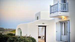 En hvid bygning med balkon, dør og udsigt over landskabet.
