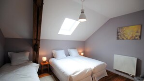 Quarto com duas camas, claraboia, radiador e um quadro na parede.