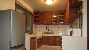 Una cocina compacta con armarios de madera, un lavamanos empotrado y un refrigerador.
