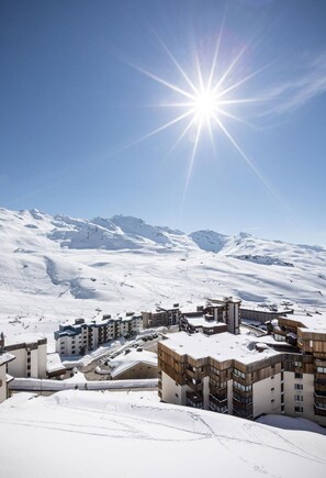 A snow-covered mountain town with modern buildings and ski slopes. - Wifi, 250m from resort center, fitness, swimming pool, sauna, hammam, balcony, tv, ski locker, 45m² (Val Thorens)