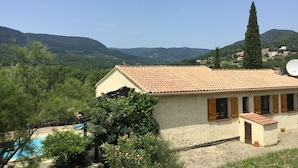 A house with a tiled roof, a swimming pool, and a view of green hills and mountains. - Secluded Villa With Private Pool (Lodève)