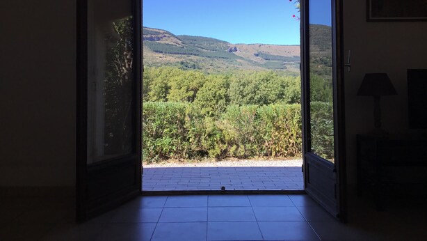 An open door leading to a balcony with a view of a forested hillside. - Secluded Villa With Private Pool (Lodève)