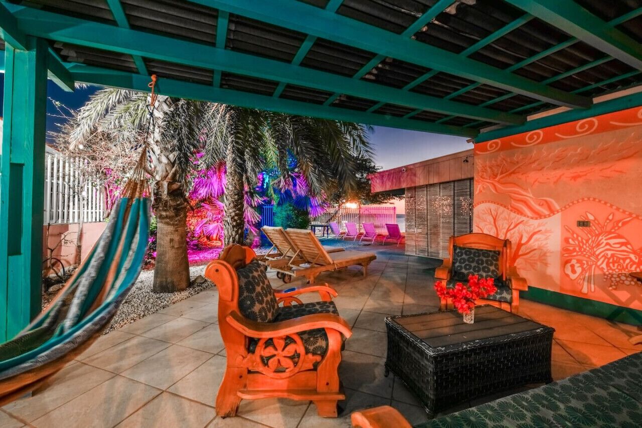 Un espace extérieur aménagé en terrasse, avec des fauteuils de jardin en bois, une table en osier noir et un hamac.