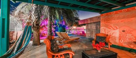 Un espace extérieur aménagé en terrasse, avec des fauteuils de jardin en bois, une table en osier noir et un hamac.