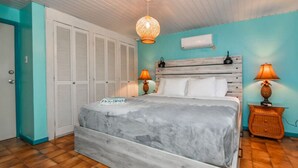 Une chambre à coucher avec un grand lit, deux lampes de chevet, un ventilateur de plafond et une armoire.