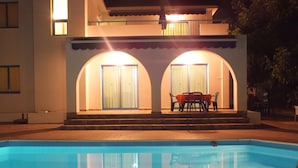 A swimming pool with a patio area featuring a table and chairs.