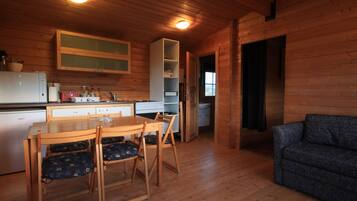Un intérieur en bois comprenant un coin repas, une kitchenette et un canapé.