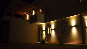 Un bâtiment moderne doté d’un balcon, d’un éclairage extérieur et d’un petit jardin.