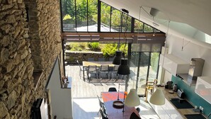 Eine moderne Küche mit Steinwand, einem Essbereich mit Tisch und Stühlen sowie Blick ins Freie.