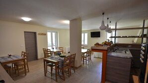 A spacious kitchen with a central island, wooden dining table, and chairs.
