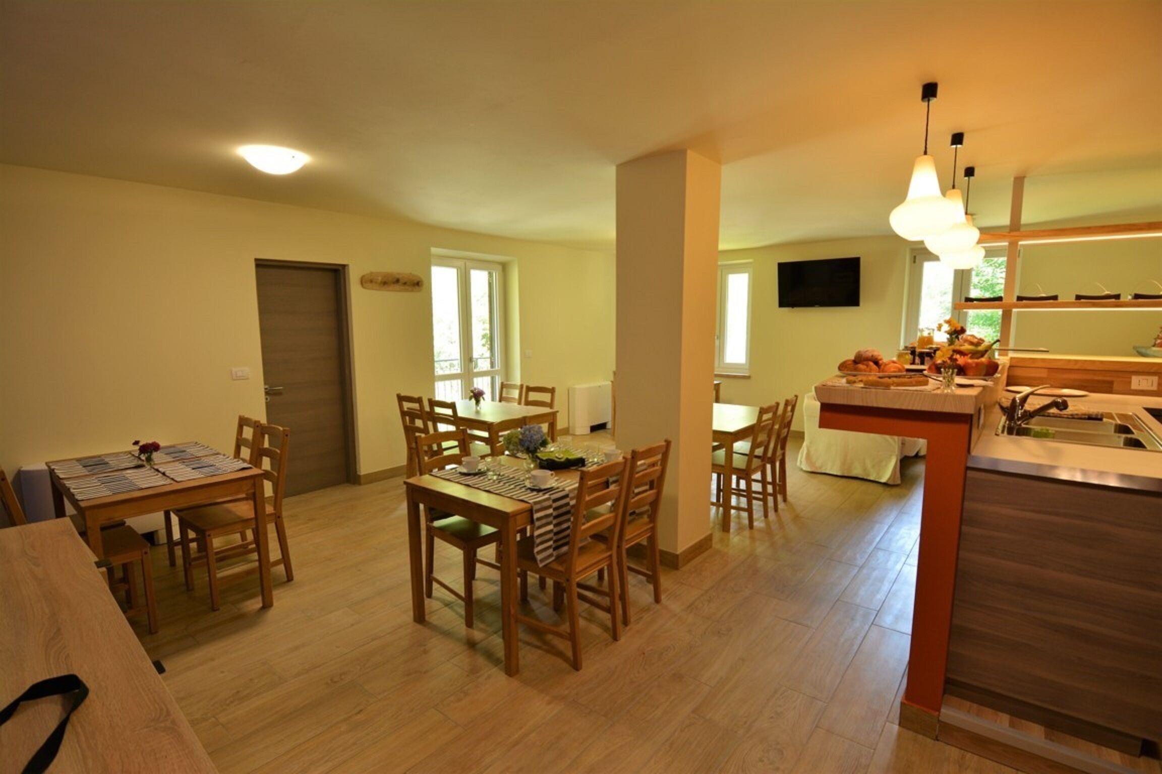 A spacious dining area with wooden furniture and a kitchen area with modern appliances.