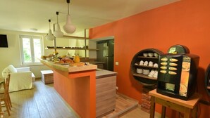 A modern kitchen with a central island, a coffee machine, and a seating area with a chair and table.