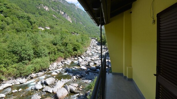 A balcony with a view of a river and mountains.