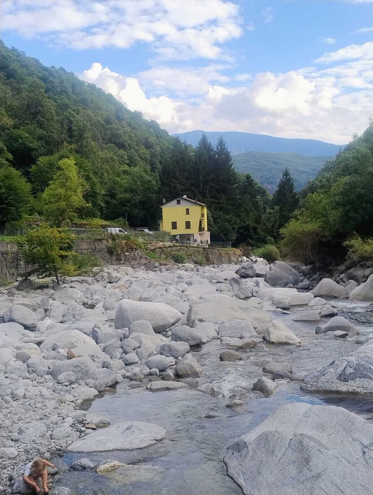 Un edificio amarillo con un muro de piedra en una zona montañosa.