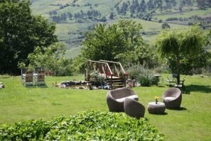 Un espace extérieur verdoyant, aménagé avec des sièges et doté d’une structure en bois.